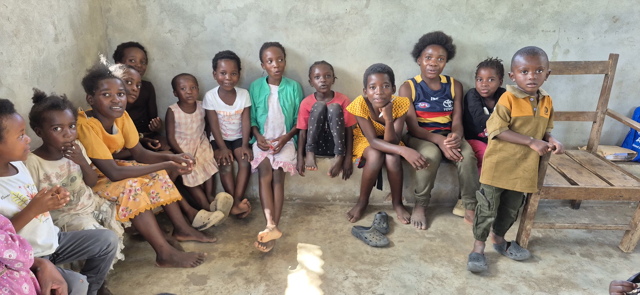 Children seated together along a wall